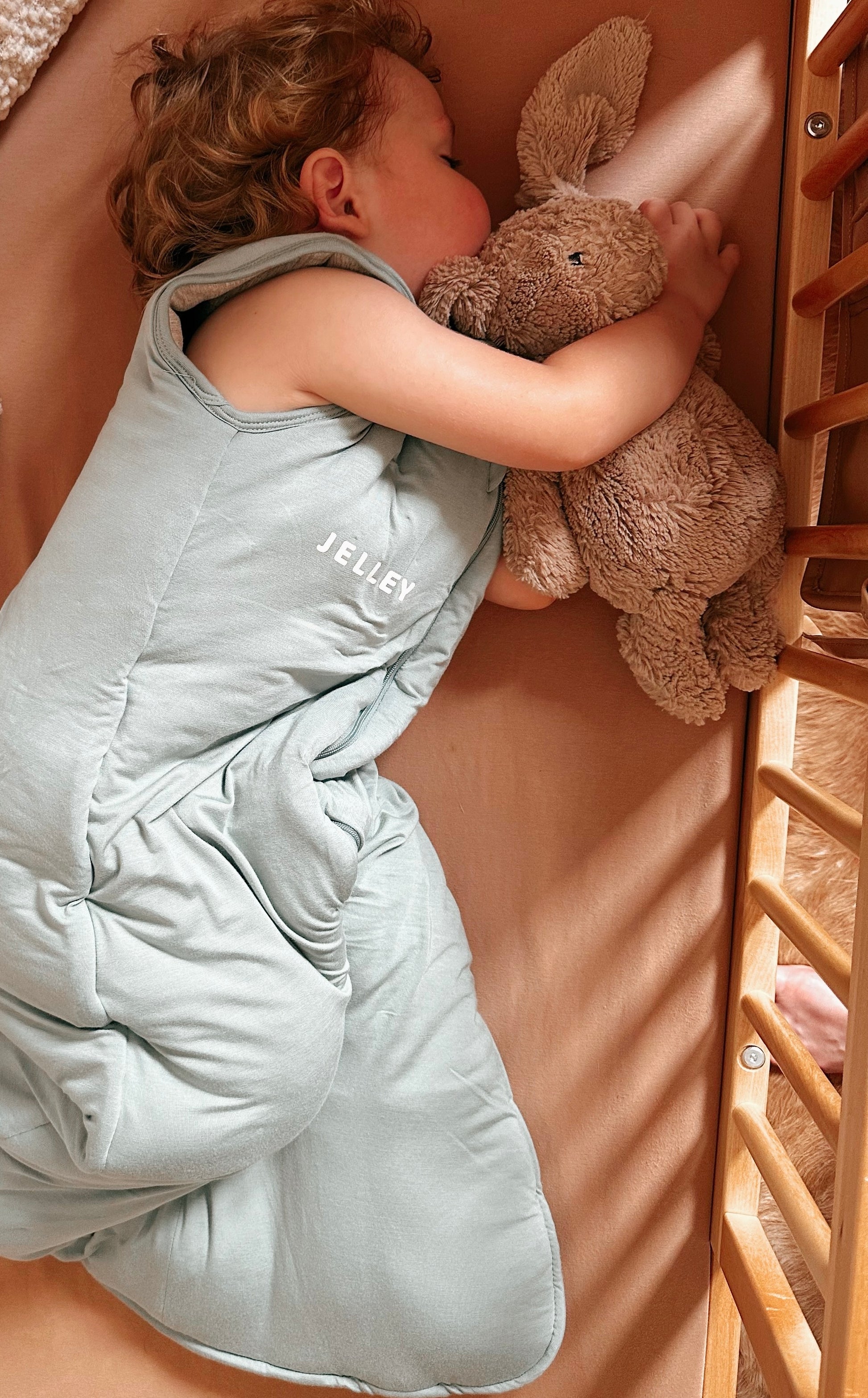 Baby wearing Jelley silver fibre sleeping bag in sage colour.